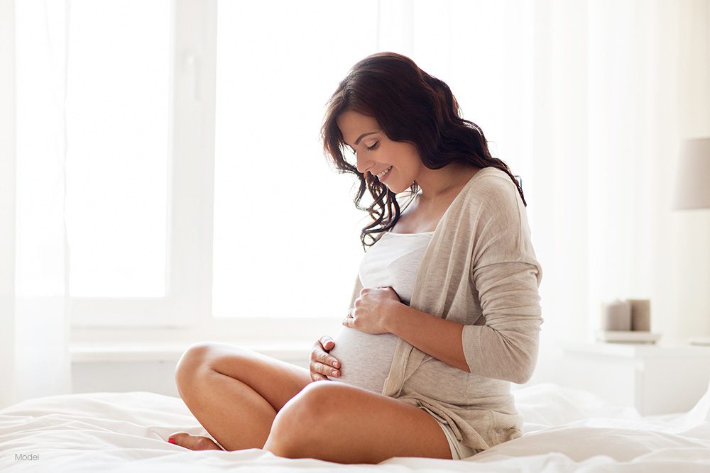 Pregnant woman sitting on a bed 